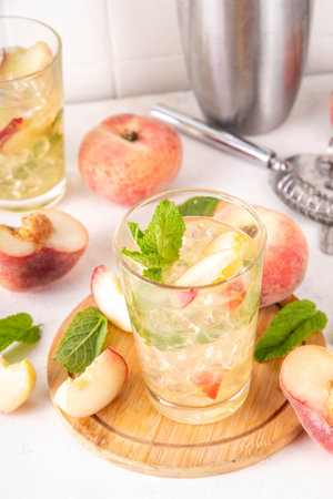 Flat peach lemonade, iced tea or mojito cocktail with fresh fruit garnish. Sweet non-alcohol flat chinese peach fig peach mocktail with peach slices, mint and crushes iceの写真素材