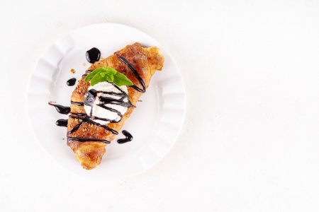 Trendy viral korean style flat croissant with ice cream and chocolate sauce, sweet sugared caramel glazed croissant for breakfast, copy spaceの写真素材