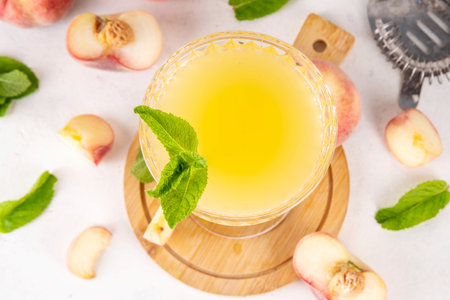 Flat peach martini or margarita lemonade cold fruit drink, summer iced fruit juice cocktail with mint and lemon, on white tableの写真素材