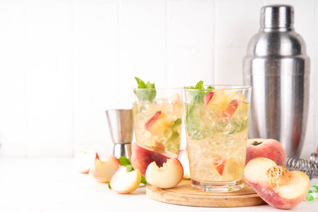 Flat peach lemonade, iced tea or mojito cocktail with fresh fruit garnish. Sweet non-alcohol flat peaches fig peach mocktail with peach slices, mint and crushes iceの写真素材