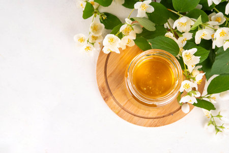 Homemade jasmine flower jam, floral golden confiture preserves with fresh jasmine flowers on white table backgroundの写真素材