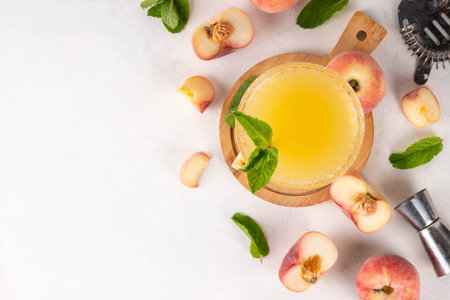 Flat peach martini or margarita lemonade cold fruit drink, summer iced fruit juice cocktail with mint and lemon, on white tableの写真素材