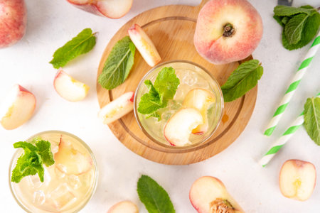 Flat peach lemonade, iced tea or mojito cocktail with fresh fruit garnish. Sweet non-alcohol flat peaches fig peach mocktail with peach slices, mint and crushes iceの写真素材