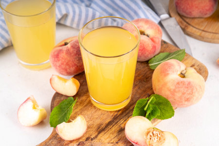 Flat peaches juice with fresh flat peaches and mint in white background copy spaceの写真素材