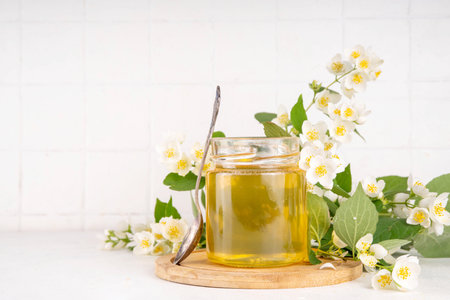 Homemade jasmine flower jam, floral golden confiture preserves with fresh jasmine flowers on white table backgroundの写真素材