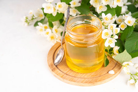 Homemade jasmine flower jam, floral golden confiture preserves with fresh jasmine flowers on white table backgroundの写真素材