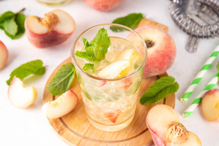 Flat peach lemonade, iced tea or mojito cocktail with fresh fruit garnish. Sweet non-alcohol flat peaches fig peach mocktail with peach slices, mint and crushes iceの写真素材