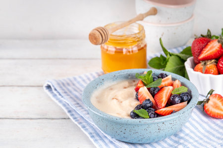 Cream of Wheat semolina porridge with fresh summer berry. Portion of breakfast whole grain creme de  semolina with dairy milk, strawberry, blueberry and honeyの写真素材