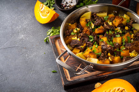 Warm pumpkin stew with potato and beef meat, comfort autumn dinner balanced food, with ingredients on kitchen tableの写真素材