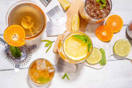 Trendy Tea Inspired cocktail set from green, oolong, black, chai and other tea blends. Sparkling tea soda, cold summer drinks with syrup, lemon, lime and mint, on sun lighted white wooden backgroundの写真素材