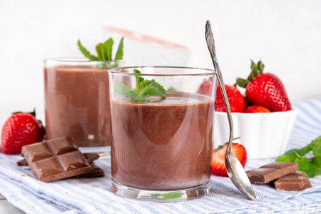 Homemade chocolate pudding dessert, in ceramic portioned bowl on kitchen table, with fresh strawberries, mint and chocolate slicesの写真素材