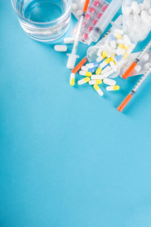 Pharmaceutical medicine pills concept, Assorted various pills, tablets and capsules with medical syringes, thermometer and water glass, copy space mockup, flatlayの写真素材