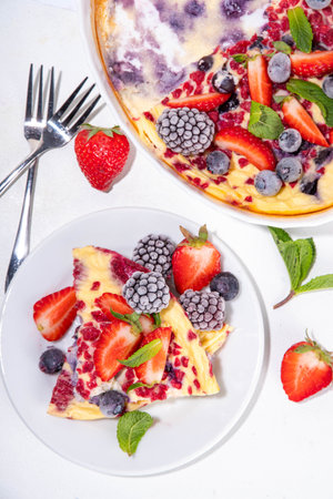 Baked yogurt healthy sweet morning dessert. Oven baked greek yogurt cake with berries, on white kitchen table, with ingredients, top viewの写真素材