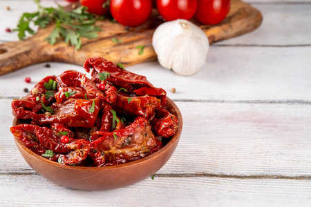 Homemade sun-dried tomatoes in olive oil, gourmet italian food ingredient, with fresh tomatoes, oil bottle and spices on kitchen tableの写真素材