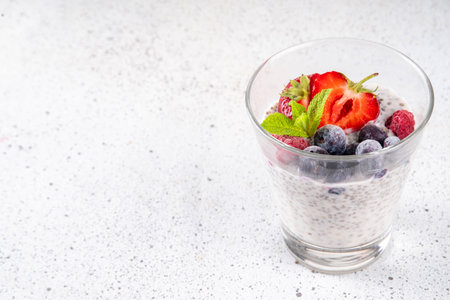Chia seeds pudding with fresh berries. Healthy summer breakfast dessert with creamy milk or yogurt, chia, strawberry and blueberry, white table background copy spaceの写真素材