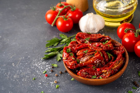 Homemade sun-dried tomatoes in olive oil, gourmet italian food ingredient, with fresh tomatoes, oil bottle and spices on kitchen tableの写真素材