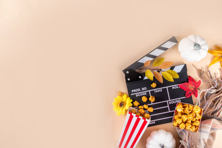 Autumn seasonal movie marathon. Cozy fall season cinema and TV-show Movie Night party. Cinema clapper-board, sweet pumpkin syrup caramel popcorn in paper cups, autumn leaves, pumpkins and decorationsの写真素材