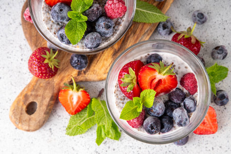 Chia seeds pudding with fresh berries. Healthy summer breakfast dessert with creamy milk or yogurt, chia, strawberry and blueberry, white table background copy spaceの写真素材