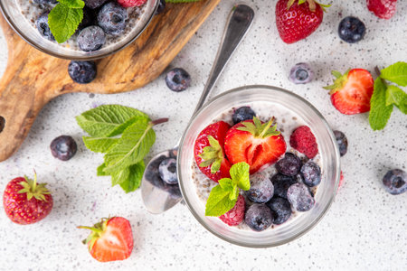 Chia seeds pudding with fresh berries. Healthy summer breakfast dessert with creamy milk or yogurt, chia, strawberry and blueberry, white table background copy spaceの写真素材