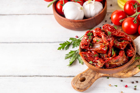 Homemade sun-dried tomatoes in olive oil, gourmet italian food ingredient, with fresh tomatoes, oil bottle and spices on kitchen tableの写真素材