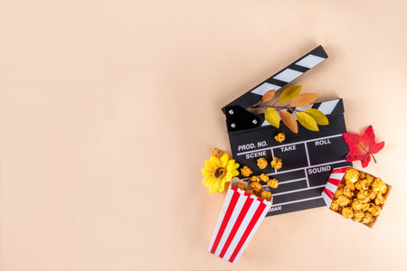 Autumn seasonal movie marathon. Cozy fall season cinema and TV-show Movie Night party. Cinema clapper-board, sweet pumpkin syrup caramel popcorn in paper cups, autumn leaves, pumpkins and decorationsの写真素材