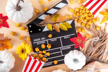 Autumn seasonal movie marathon. Cozy fall season cinema and TV-show Movie Night party. Cinema clapper-board, sweet pumpkin syrup caramel popcorn in paper cups, autumn leaves, pumpkins and decorationsの写真素材