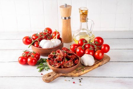 Homemade sun-dried tomatoes in olive oil, gourmet italian food ingredient, with fresh tomatoes, oil bottle and spices on kitchen tableの写真素材