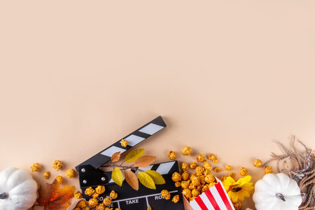 Autumn seasonal movie marathon. Cozy fall season cinema and TV-show Movie Night party. Cinema clapper-board, popcorn in paper cups, autumn leaves, pumpkins and decorationsの写真素材