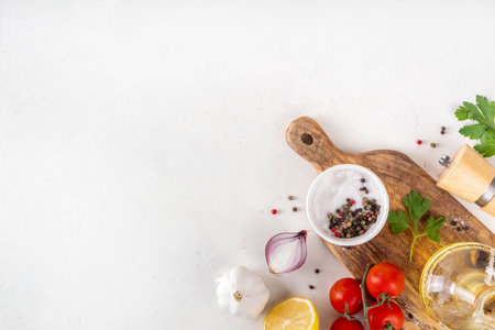 Spices, black pepper, garlic, onion, greens and tomatoes, olive oil on white cooking table. Ingredients for cooking food on the white stone concrete background top view copy space.の写真素材
