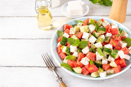 Viral summer Watermelon Salad with slices red watermelon, cucumber, white feta or tofu cheese, herbs, with olive oil and spices, copy spaceの写真素材