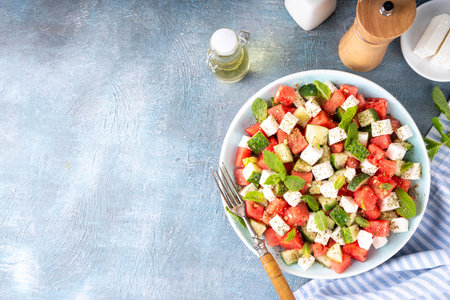 Viral summer Watermelon Salad with slices red watermelon, cucumber, white feta or tofu cheese, herbs, with olive oil and spices, copy spaceの写真素材