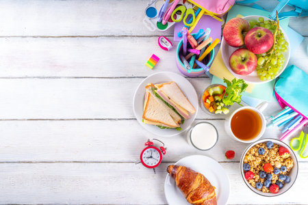 Healthy nutritious  morning breakfast for school kids, with fresh fruits, vegetables, croissant, muesli, milk and sandwich. Having breakfast before school and work, copy spaceの写真素材