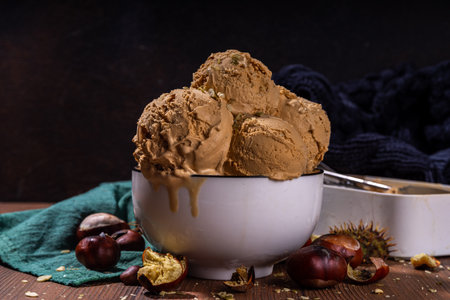 Autumn spicy ice cream with the roasted chestnut taste, with spices, on a wooden background with fresh and roasted chestnutsの写真素材