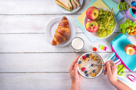 Healthy nutritious  morning breakfast for school kids, with fresh fruits, vegetables, croissant, muesli, milk and sandwich. Child girl having breakfast before school and work, copy spaceの写真素材