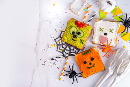 Kids food, party or breakfast Halloween idea. Simple healthy sandwiches recipe from toast bread, avocado, cream cheese, pumpkin spread with Halloween monster decorの写真素材