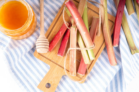 Raw fresh organic rhubarb stems on kitchen table background, bunch of homegrown pink and green rhubarb ready for cooking, on cutting board. Summer harvest, summer food and dessert cooking ingredientの写真素材