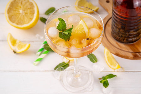 Infused tasty iced tea cocktails martini cocktail with lemon and mint, tasty refreshing non-alcohol mocktail on white wooden table backgroundの写真素材