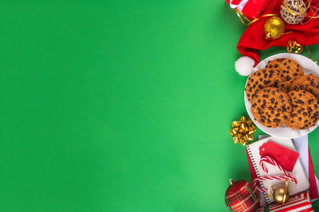 Christmas festive background with tasty hot chocolate, crispy chocolate drops cookies, Christmas decor, baubles, santa hat and gift boxes, high-colored bright red green background copy spaceの写真素材