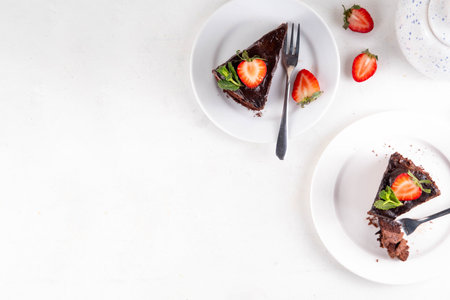 Dark chocolate cake slices, with chocolate cream and strawberry, on portioned plates, copy spaceの写真素材