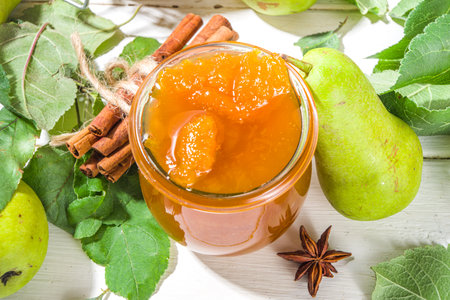 Homemade golden colored pear jam, with farm pears and leaves on white wooden background copy spaceの写真素材