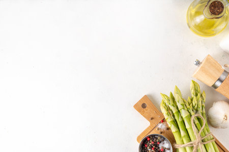 Raw fresh organic asparagus stems on kitchen table background, bunch of homegrown green asparagus ready for cooking, on cutting board. Summer harvest, summer food cooking ingredientの写真素材