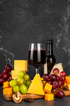 Tasty delicious cheese and dried sausage appetizers board, with wine, nuts, grapes fruits, antipasto brunch snack, copy spaceの写真素材