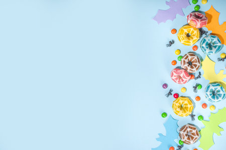 Trendy bright colorful Halloween background, with paper purple, blue, yellow, orange Halloween symbols - bats, ghost, sweets and candies. Light blue background, flatlay top view copy spaceの写真素材