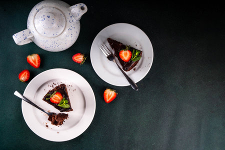 Dark chocolate cake slices, with chocolate cream and strawberry, on portioned plates, copy spaceの写真素材