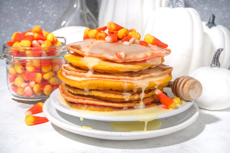 Homemade candy corn pancakes. Stack of yellow and orange pancakes with sweet sauce and traditional Halloween candy cord candiesの写真素材