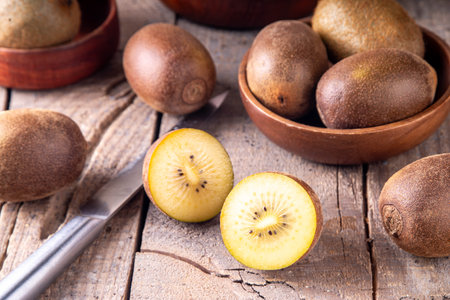 Sweet golden kiwi fruits, whole and sliced, on kitchen table copy spaceの写真素材