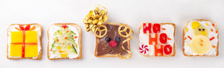 Christmas funny creative toasts sandwich for kids breakfast. Homemade Christmas morning sandwiches in form of gift, Christmas tree, deer, snowman, penguin, with cheese, fruit, chocolate, vegetablesの写真素材