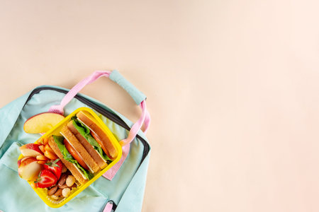 Back to school. Healthy school meal, children packed lunch box with fruit, berry, nuts, sandwich with vegetables. Kids diet snack food with education school supplies, bright blue background top viewの写真素材