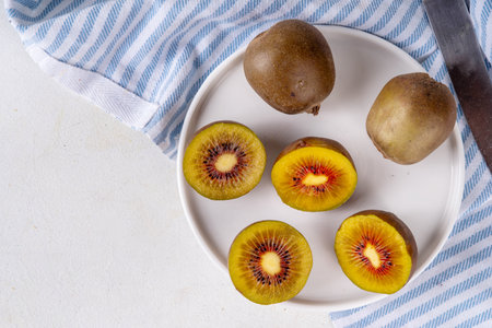 Red kiwi, Sweet bright red colored kiwi fruits, whole and sliced, on kitchen table copy spaceの写真素材