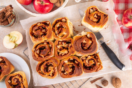 Apple cinnamon roll, sweet cinnabon buns with apple filling. Viral apple pie rolled buns, on beige table with cinnamon sticks, apples, nuts and spicesの写真素材
